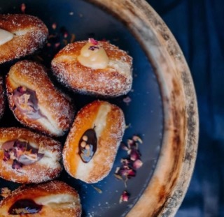 Freshly filled doughnuts dusted with sugar and rose petals